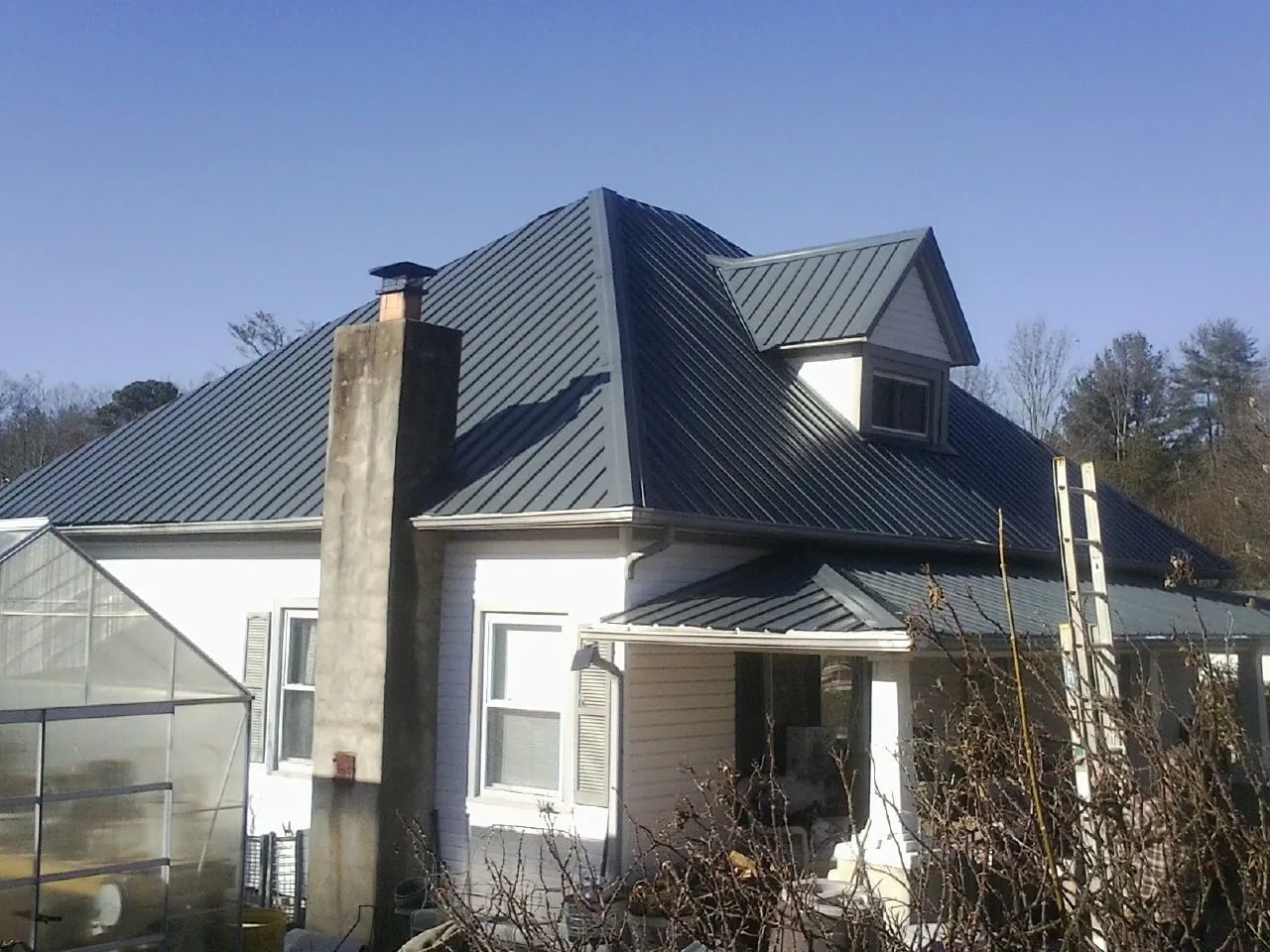 Dark blue standing seam metal roof on a white farmhouse with dormer — Slate & Tile Roof Repair by Roofing Brothers in Orleans