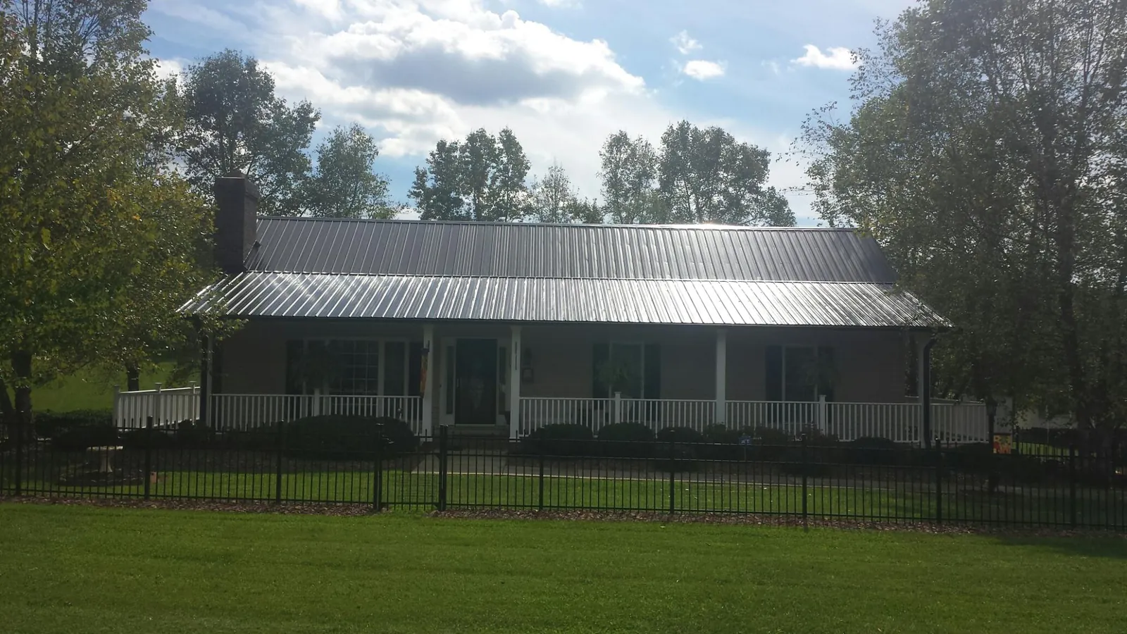 Gray metal roof on a brick ranch with a full width front porch — Gutter Guard Installation work by our crew in Orleans