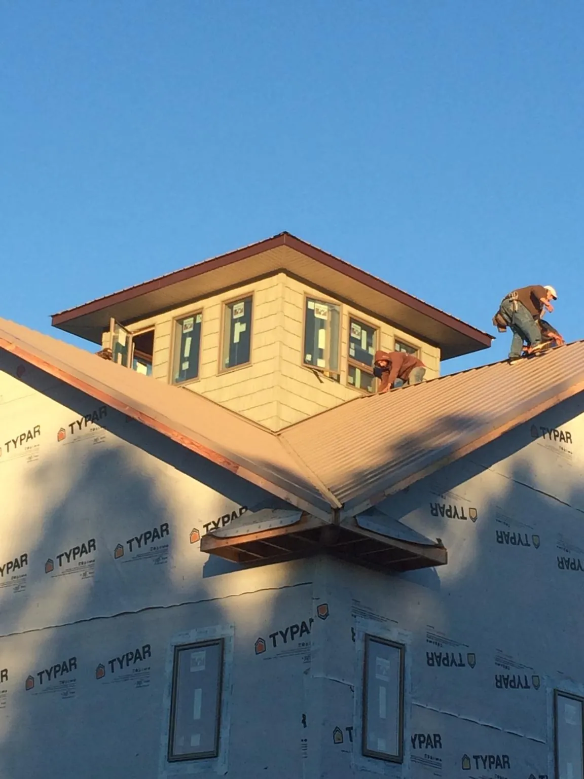 Roofers working around a rooftop cupola on a new metal roof at sunset — Roof Waterproofing in Orleans by Roofing Brothers